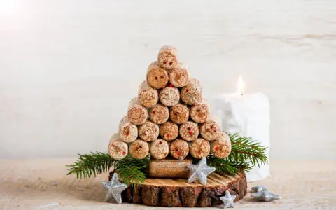 Weihnachtsbaum aus Korken, ein tolles Bastelprojekt für Erwachsene. Mit Tannenzweigen und Sternen dekoriert, neben einer Kerze.