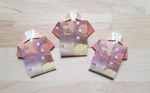 Drei Origami-Hemden aus Geldscheinen. Das letzte Hemd falten ist eine Kunst für sich.