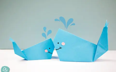 Zwei niedliche Origami-Wale, die Wasser spritzen.