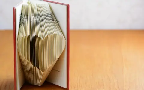 Ein Buch, dessen Seiten zu einem Herz gefaltet sind. Eine kreative Idee für ein Geldgeschenk, Buch basteln.