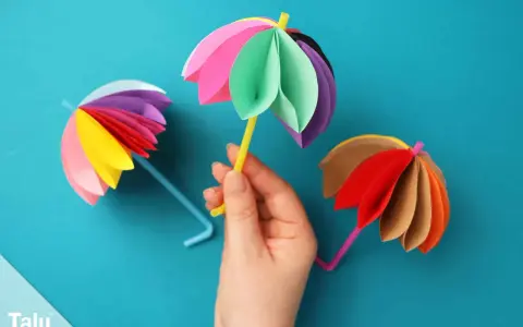Bunte Papier-Regenschirme, tolle bastelideen einfach und schnell für Kinder. Ein gelber Schirm wird von einer Hand gehalten.