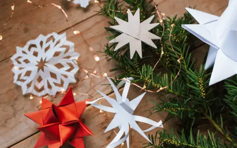 Zauberhafte Papier bastelideen Weihnachten einfach: Sterne aus Papier, Tannenzweige und Lichterkette auf Holz.