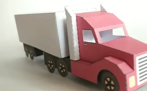 Ein roter LKW mit weißem Auflieger, liebevoll aus Papier gebastelt.