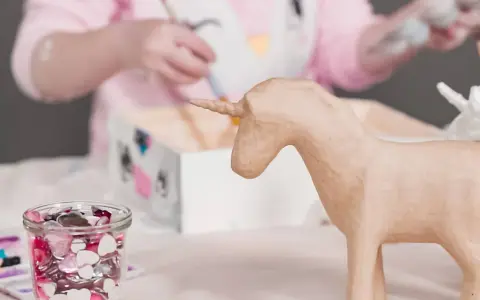 Ein Kind bastelt einfache Pappmache Figuren, hier ein Einhorn.