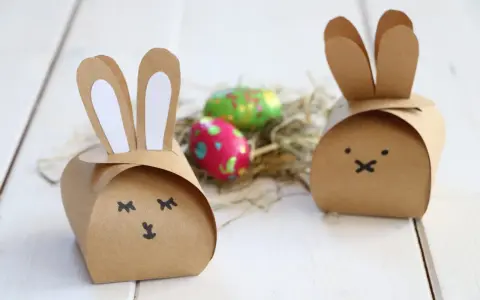 Zwei niedliche Osterhasen-Schachteln aus Pappe, inspiriert von einer Vorlage, mit bunten Ostereiern im Nest.