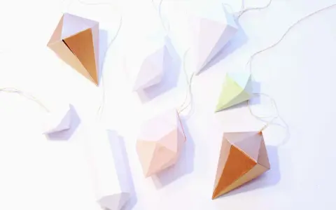 Papierdiamanten in verschiedenen Farben und Größen, die an goldenen Fäden hängen. Eine tolle Idee für eine diamant basteln vorlage.