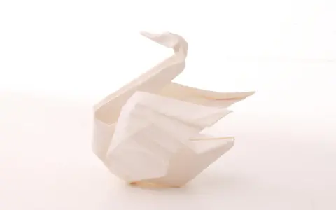 Ein weißer Origami-Schwan, der Eleganz und Reinheit symbolisiert. Die Bedeutung des Origami-Schwan steht für Glück und Treue.