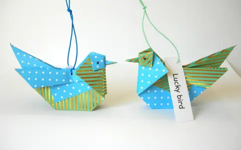 Zwei Origami-Vögel, die zum **Vogel Mobile basteln** einladen. Einer mit Punkten, der andere mit Streifen.