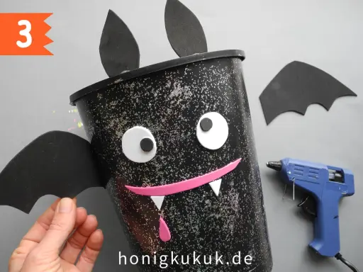 Schritt 3: Ein Fledermaus-Eimer für Halloween basteln. Mit Heißkleber und Bastelmaterialien entsteht ein gruseliger Hingucker.