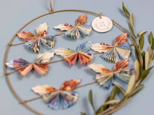 Kreative Deko: Viele bunte Schmetterlinge, gefaltet aus Geld, hängen an einem Ring. Ein schönes Geschenk, um Freude zu schenken.