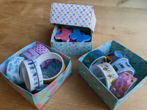 Bunte schachtel falten mit deckel, gefüllt mit Washi-Tapes und Glitzer-Schmetterlingen.