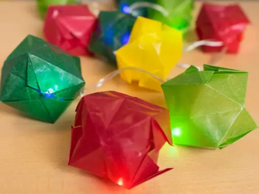 Bunte Origami-Würfel leuchten auf einer Lichterkette. Eine Anleitung für diese origami lichterkette anleitung wäre toll.
