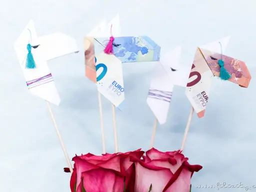 Origami-Pferde aus Geld gefaltet, mit bunten Quasten und Rosen. Ein kreatives Geldgeschenk.