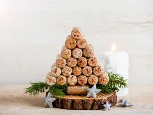 Weihnachtsbaum aus Korken, ein tolles Bastelprojekt für Erwachsene. Mit Tannenzweigen und Sternen dekoriert, neben einer Kerze.