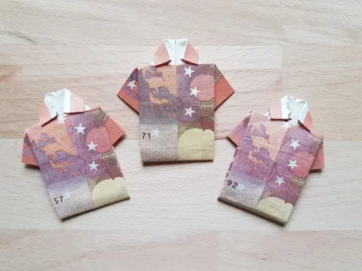 Drei Origami-Hemden aus Geldscheinen. Das letzte Hemd falten ist eine Kunst für sich.