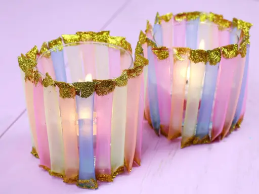 Zwei bunte Windlichter, die Kinder mit Papier und Glitzer basteln können. Sie leuchten sanft.