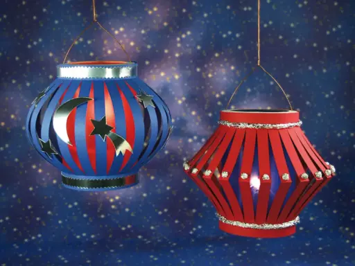 Zwei selbstgebastelte Lampions, die zum Lampion falten einladen. Einer mit Mond und Sternen, der andere mit funkelnden Steinchen.
