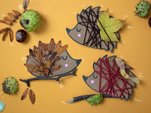 Drei Igel-Bastelvorlagen aus Papier mit Blättern, Garn und Ästen. Ein Igel hat braunes Garn, ein anderer Herbstblätter, der dritte ist mit roten Garn verziert.