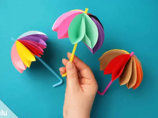 Bunte Papier-Regenschirme, tolle bastelideen einfach und schnell für Kinder. Ein gelber Schirm wird von einer Hand gehalten.