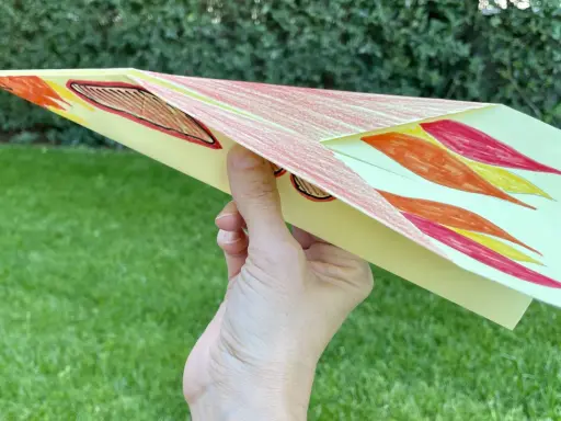 Bunter Papierflieger mit Flammenmuster, bereit zum Abheben. Hier ist die papierflieger anleitung zum ausdrucken.