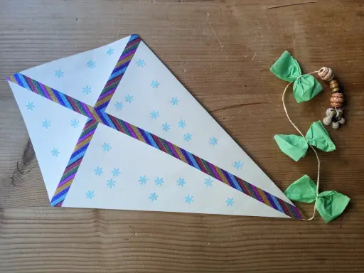 Ein selbstgebastelter Drachen mit Schneeflockenmuster und bunten Bändern, ideal als bastelvorlagen kinder.