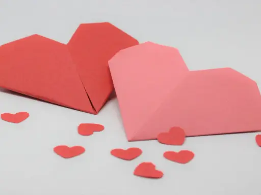 Zwei Origami-Herzen, rot und rosa, umgeben von kleinen roten Herzen. Perfekt zum **Herzen basteln** für den Valentinstag.