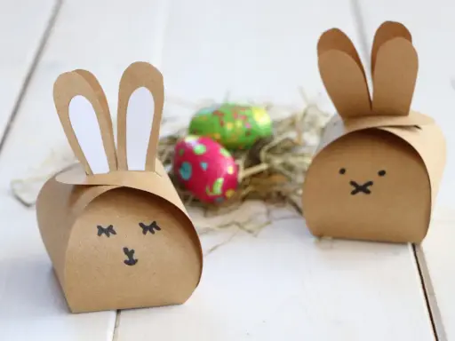 Zwei niedliche Osterhasen-Schachteln aus Pappe, inspiriert von einer Vorlage, mit bunten Ostereiern im Nest.