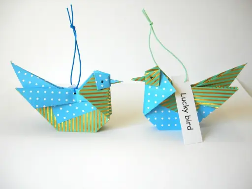 Zwei Origami-Vögel, die zum **Vogel Mobile basteln** einladen. Einer mit Punkten, der andere mit Streifen.