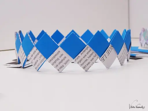Eine selbstgebastelte Geburtstagskrone aus Papierstreifen, blau und weiß, mit Text bedruckt. Perfekt zum Geburtstagskrone basteln!