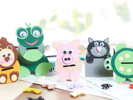 Vier selbstgebastelte Spardosen in Tierform: Löwe, Frosch, Schwein und Katze. Eine Schildkröte steht daneben.