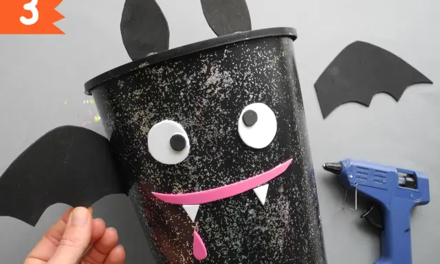 Schritt 3: Ein Fledermaus-Eimer für Halloween basteln. Mit Heißkleber und Bastelmaterialien entsteht ein gruseliger Hingucker.