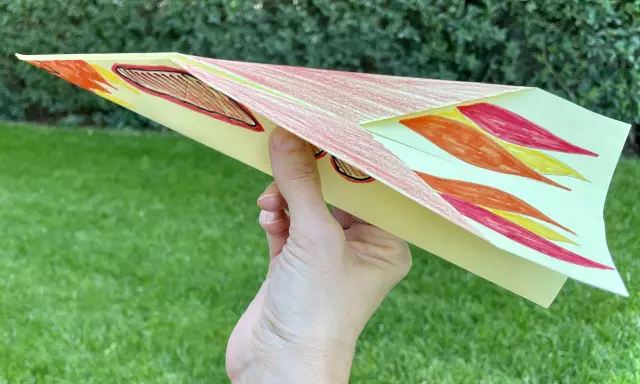 Bunter Papierflieger mit Flammenmuster, bereit zum Abheben. Hier ist die papierflieger anleitung zum ausdrucken.