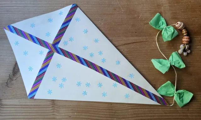 Ein selbstgebastelter Drachen mit Schneeflockenmuster und bunten Bändern, ideal als bastelvorlagen kinder.