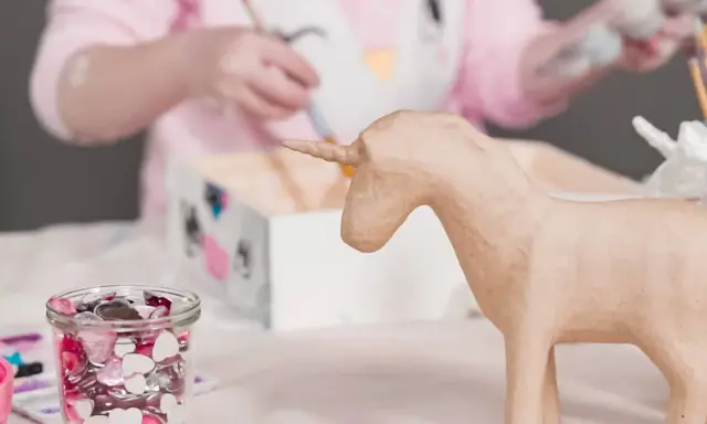 Ein Kind bastelt einfache Pappmache Figuren, hier ein Einhorn.