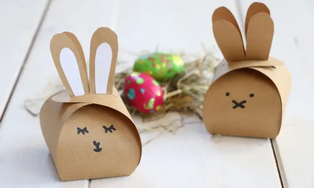 Zwei niedliche Osterhasen-Schachteln aus Pappe, inspiriert von einer Vorlage, mit bunten Ostereiern im Nest.