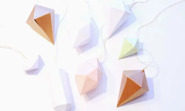 Papierdiamanten in verschiedenen Farben und Größen, die an goldenen Fäden hängen. Eine tolle Idee für eine diamant basteln vorlage.