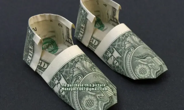 Zwei kunstvoll gefaltete Schuhe aus Geldscheinen, die wie kleine Ballerinas aussehen.