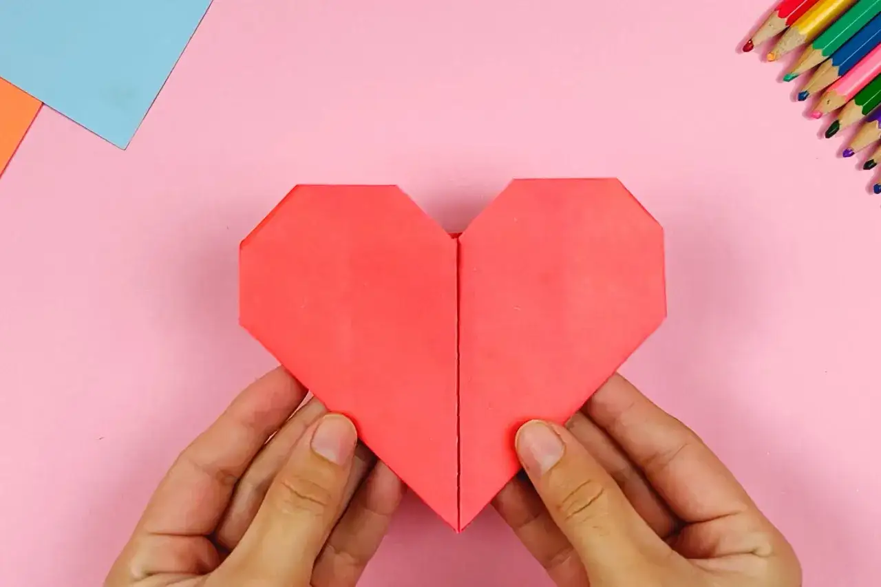 H&auml;nde falten ein rotes Papierherz. Perfekt zum Herzen basteln f&uuml;r Valentinstag oder als Dekoration.