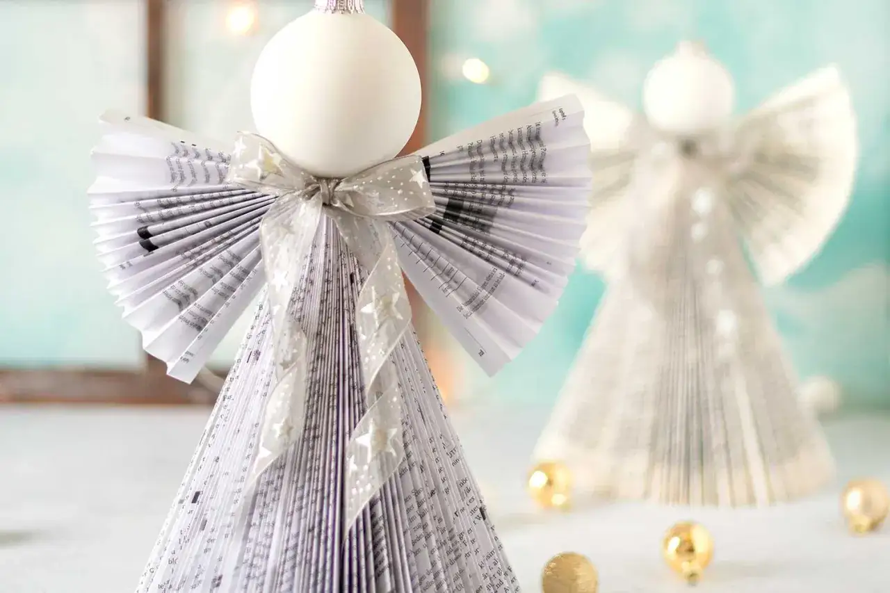 Zwei bezaubernde Origami Weihnachts Engel aus Buchseiten, verziert mit Schleifen und Sternen.