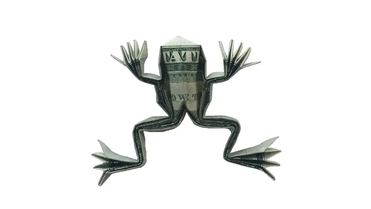 Ein Frosch aus gefaltetem Geld, der mit seinen Armen und Beinen in die Luft springt.