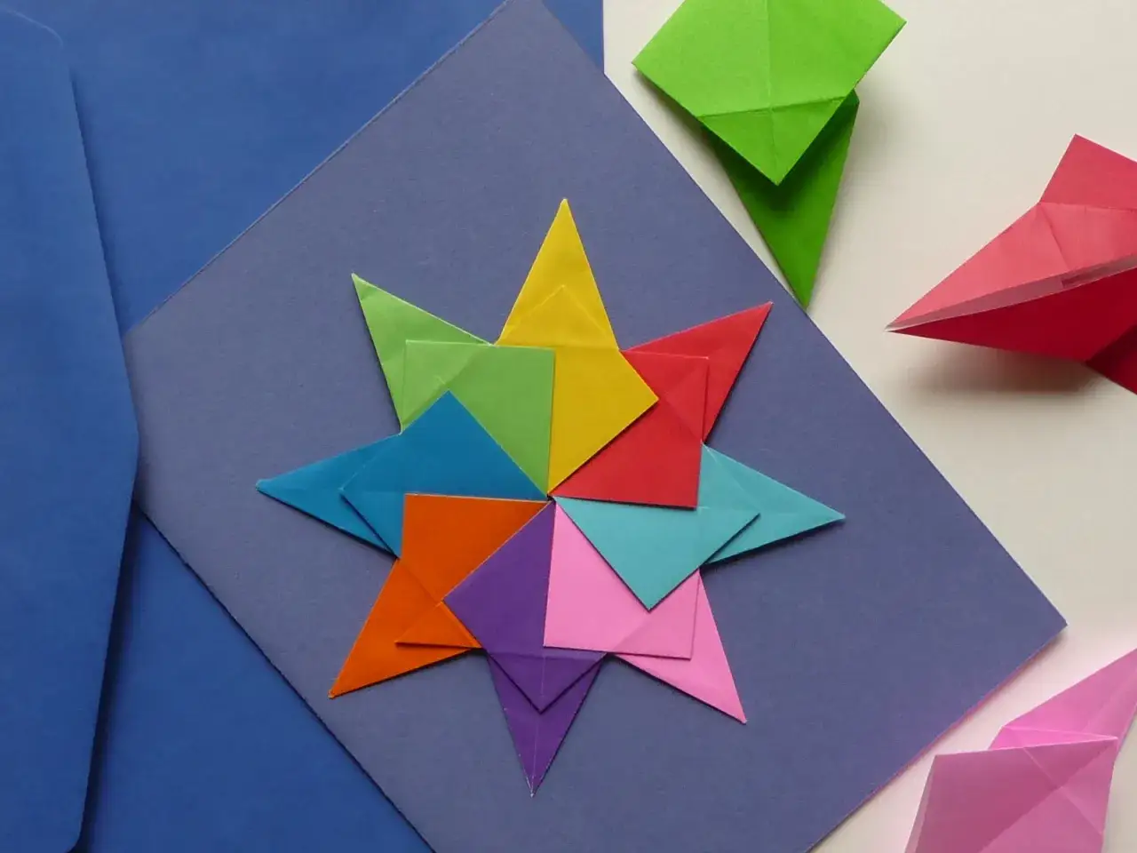 Bunte Origami-Sterne als Bastel Ideen, die auf blauem Papier arrangiert sind.