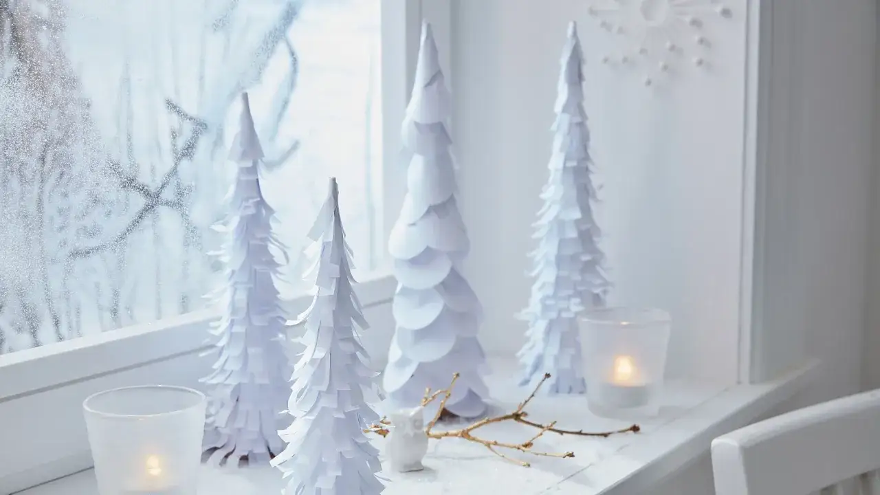 Weiße Papierbäume und Kerzenlicht auf der Fensterbank – tolle Bastelideen Weihnachten kostenlos für eine winterliche Deko.