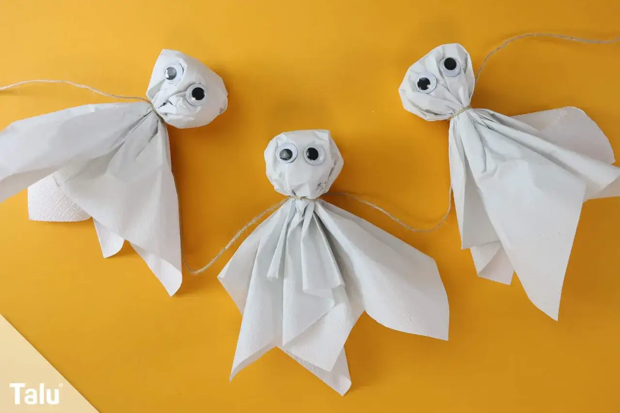 Drei s&uuml;&szlig;e Geister aus Papier mit Knopfaugen, die an einer Schnur h&auml;ngen. Perfekt f&uuml;r gespenster basteln vorlagen.