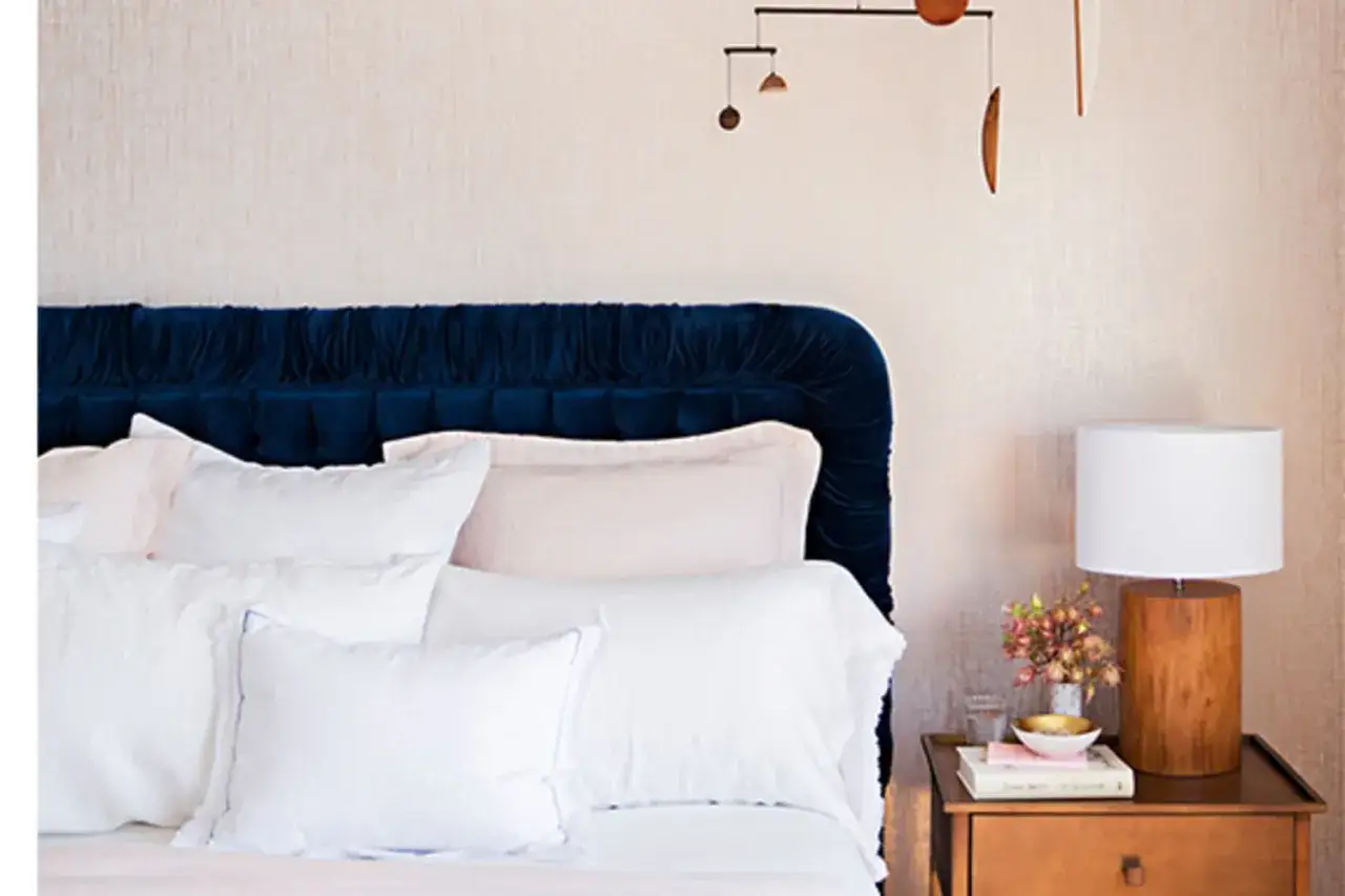 Ein stilvolles Schlafzimmer mit einem blauen Samtkopfteil und einem modernen Mobile. Hier kann man sich vorstellen, wie mobile erwachsene basteln und entspannen.