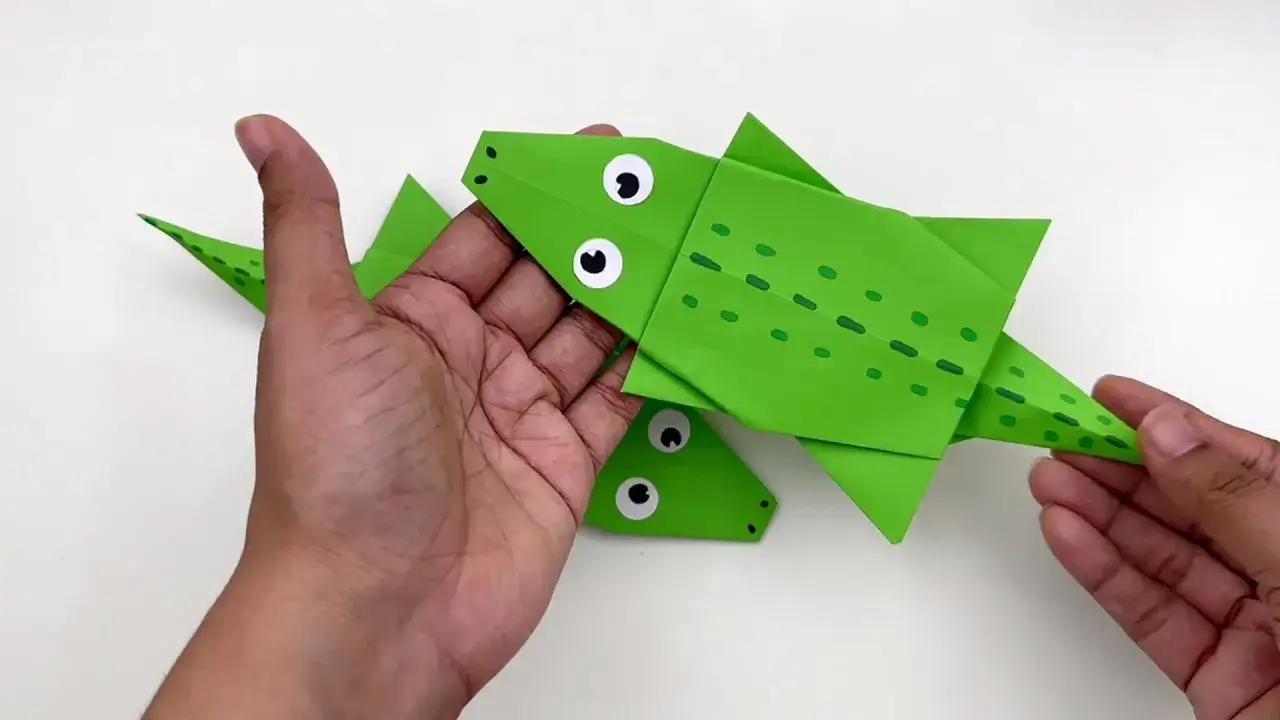 Gr&uuml;ne Papierkrokodile, die zum Schnappi falten bereit sind, mit gro&szlig;en Augen und Tupfen.