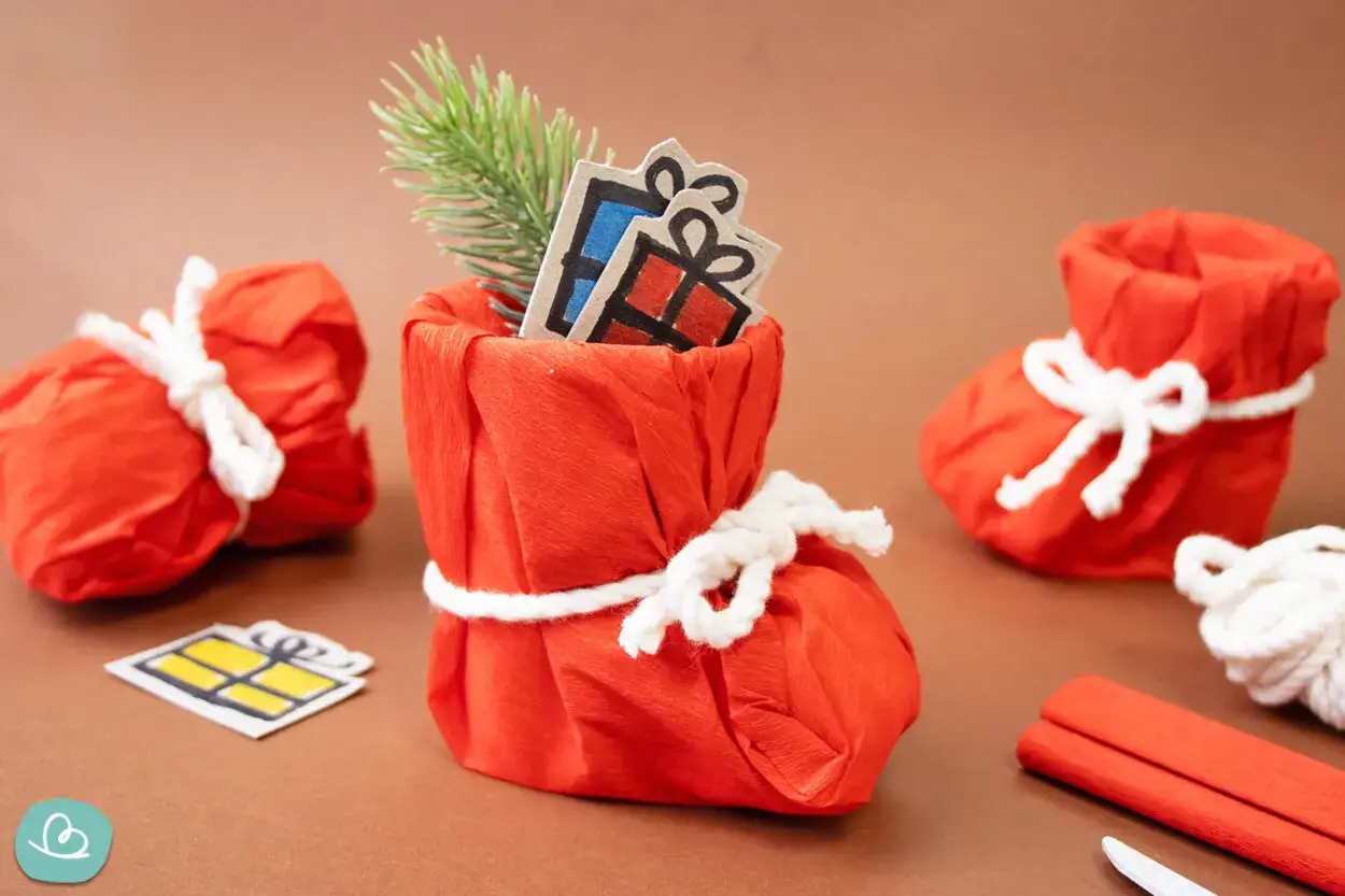 Kreative Weihnachtssocken aus gefaltetem Papier, gef&uuml;llt mit Geschenken und Tannenzweigen. Eine tolle Idee f&uuml;r Geld falten Socke.