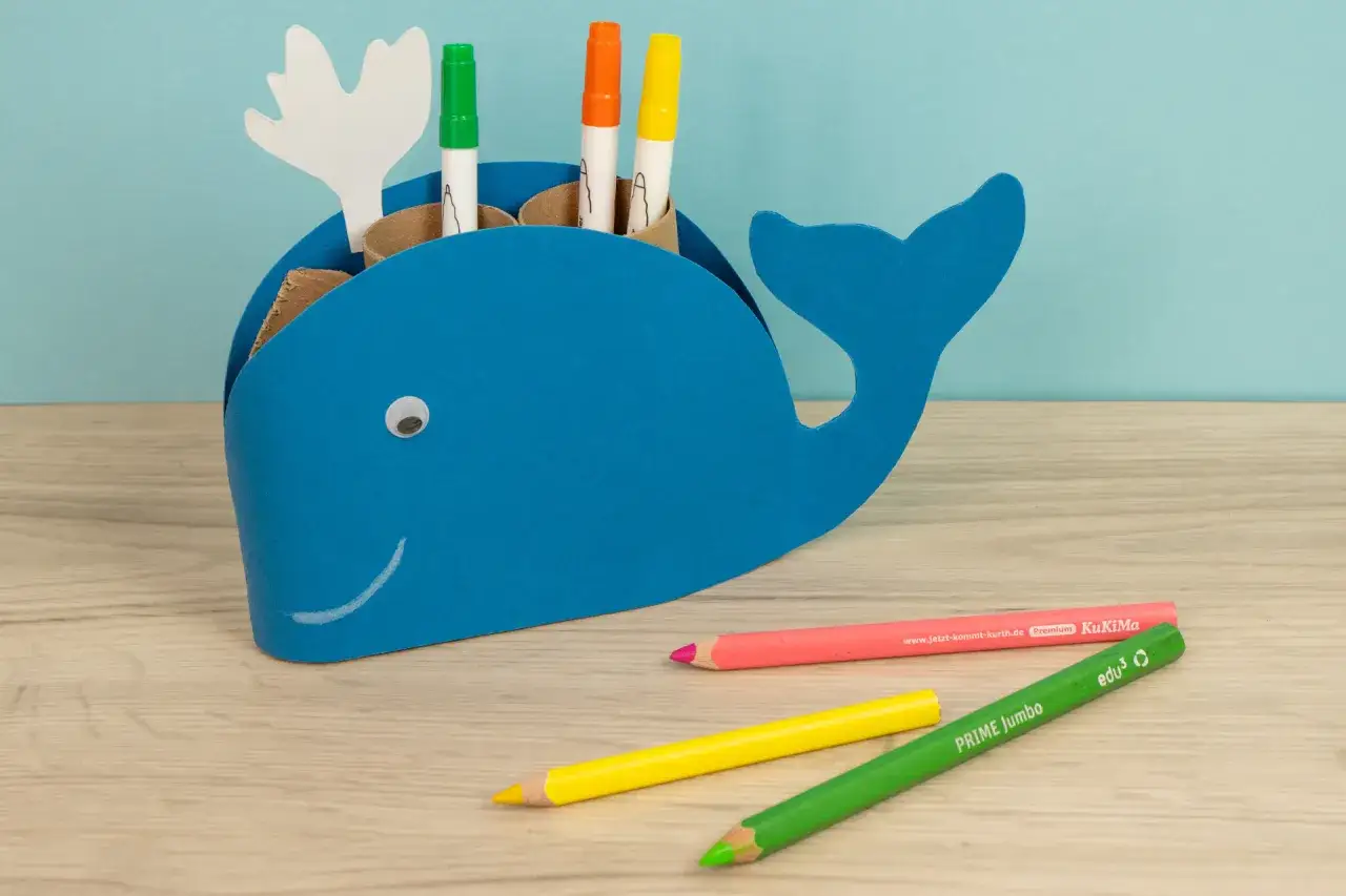 Blauer Wal-Stiftehalter basteln: Ein lustiges DIY-Projekt f&uuml;r Kinder. Bunte Stifte und ein aufgemalter Mund machen den Wal lebendig.
