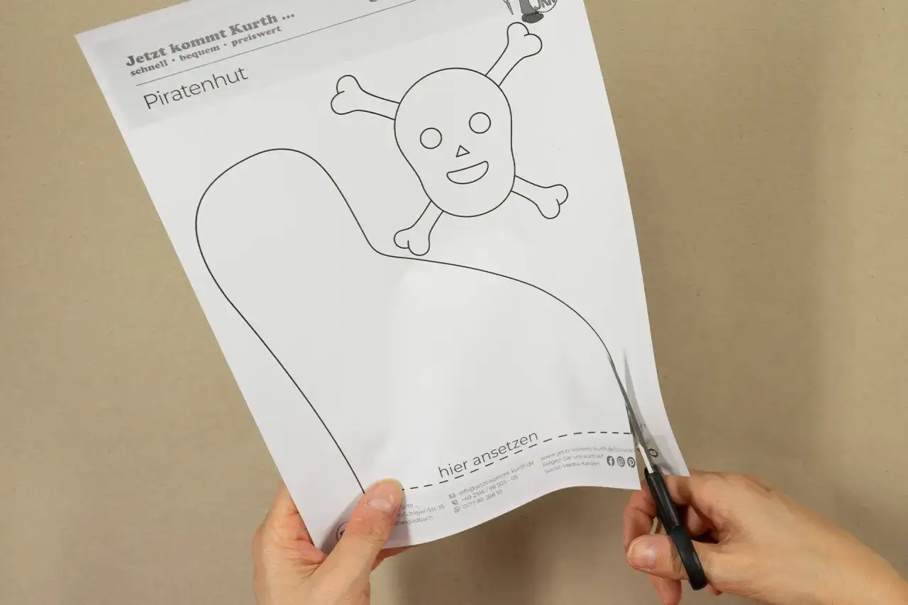 Schere schneidet Vorlage f&uuml;r einen Piratenhut mit Totenkopf. Perfekt zum Piratenhut basteln f&uuml;r Kinder.