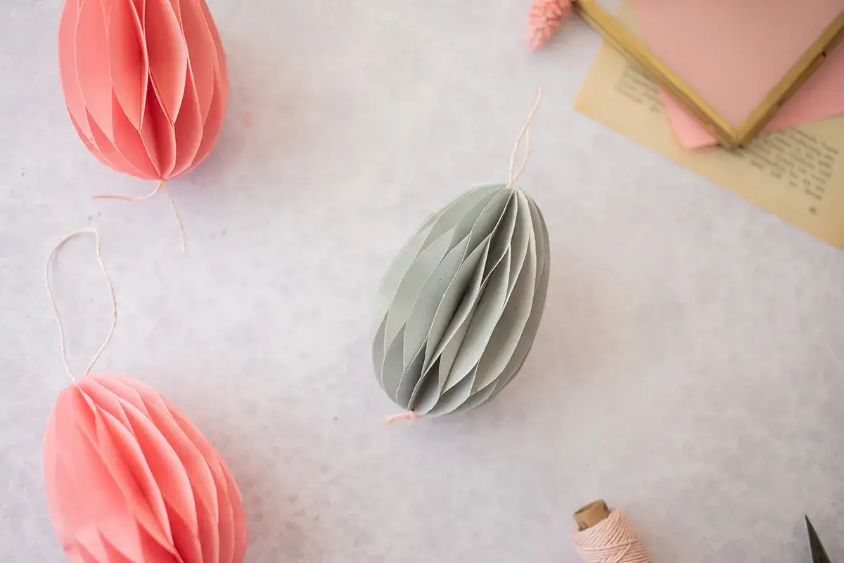 Ostereier basteln Papier: Dekorative Papier-Eier in Rosa und Grau, bereit zum Aufh&auml;ngen.