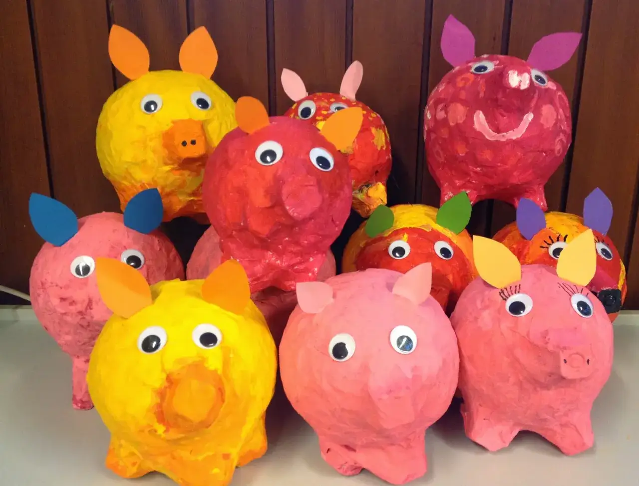 Bunte Luftballon Pappmache Tiere, haupts&auml;chlich Schweinchen, mit gro&szlig;en Kulleraugen und Papierohren, stehen fr&ouml;hlich nebeneinander.